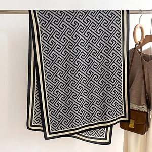 Detail of grey geometric Greek pattern scarf displayed on a hanger with fashion accessories