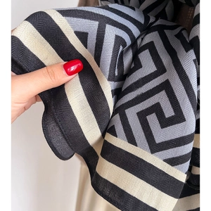 Detailed view of luxury herringbone knit scarf with geometric greek key pattern texture