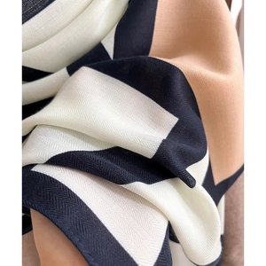 Macro detail of silk-like scarf featuring herringbone weave and contrast color blocks