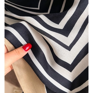 Dettaglio macro di sciarpa a righe in twill con motivo a V bianco e nero e bordi albicocca