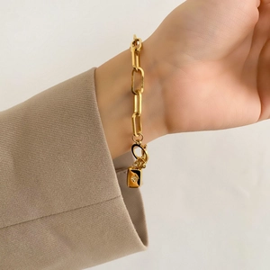 Gros plan d'un bracelet trombone doré avec pendentif étoile porté au poignet