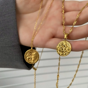 Dettaglio di collane in monete d'oro con ciondoli a rilievo di leone e angelo su catena