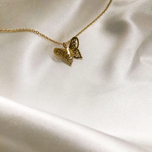 Minimalist gold-plated hollow butterfly pendant necklace on white satin background