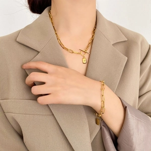Gros plan sur un ensemble collier et bracelet en maille trombone dorée avec pendentif étoile