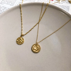 Dettaglio di collane a strati con monete d'oro con rilievi di angelo e leone su catene
