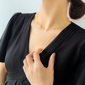Close-up of golden minimalist disc necklace on model with black dress for elegant look