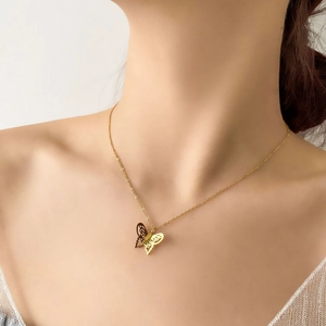 Gold plated hollow butterfly pendant necklace on a delicate chain worn by a model