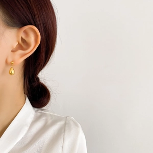 Minimalist gold teardrop earrings with mirror polish finish on a professional model