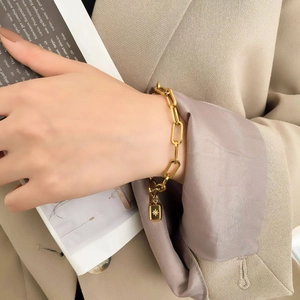 Détail d'un bracelet à maillons dorés avec pendentif rectangulaire à étoile sur le poignet