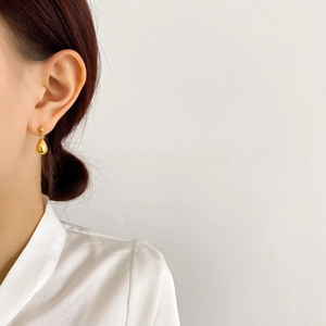 Minimalist 18K gold water drop earrings with mirror polished finish on female model