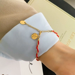 Detail of red braided bracelet with golden Double Happiness pendant and adjustable chain