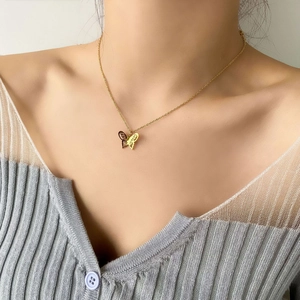 Detail of gold butterfly pendant with asymmetric hollow wing design on thin cable chain