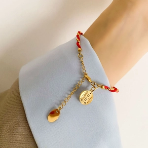 Close-up of red and gold bracelet with double charms on model wrist showing woven texture