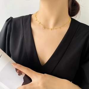 Detail of 18k gold plated choker necklace with small circular charms on a female model