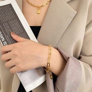 Parure de bijoux dorés avec chaîne épaisse et pendentifs étoile sur veste beige