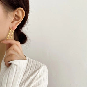 Dettaglio di eleganti orecchini a torsione a forma di U dorati dallo stile minimalista
