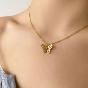 Close-up of gold plated butterfly pendant with intricate hollow wings on a chain