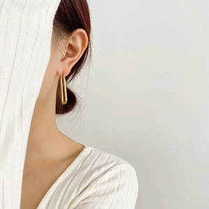 Orecchini a cerchio a U intrecciati dorati minimalisti indossati da una modella