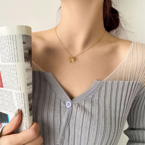 Elegant gold-plated hollow butterfly pendant necklace on a model with a gray cardigan