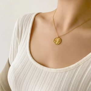 Dettaglio di una collana con ciondolo a moneta d'oro con rilievo animale su modella