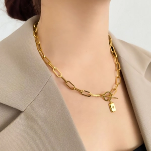 Détail d'un collier doré à gros maillons avec fermoir en T et pendentif étoile gravé