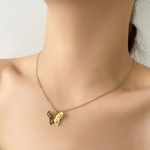 Macro detail of gold plated hollow butterfly pendant necklace on collarbone