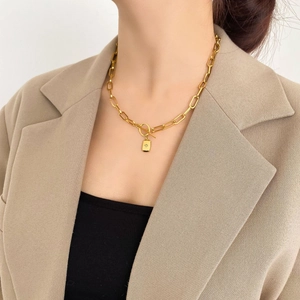 Détail du collier chaîne dorée à gros maillons avec pendentif rectangulaire et fermoir en T