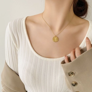 Dettaglio della collana con ciondolo a moneta d'oro e rilievo di leone su modella