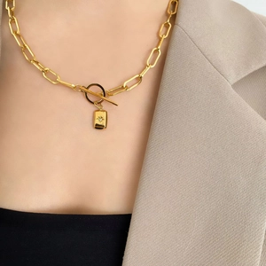 Détail du collier à trombones dorés avec pendentif étoile sur un mannequin en tailleur beige