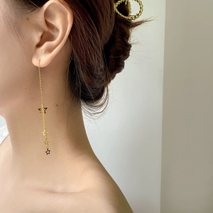 Detail view of gold star tassel earrings showing the elegant long chain drop design