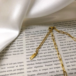 Macro detail of 18K gold-plated necklace chain with K18 stamp on vintage book background