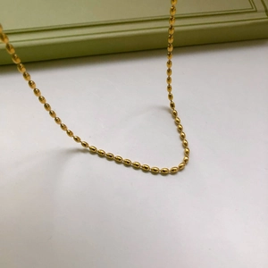 Dettaglio della catena di perle placcata oro con perle ovali lisce e riflettenti