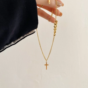 Détail d'un collier croix doré présentant un design de chaîne mixte et une finition polie