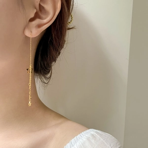 Close-up of long gold star tassel earrings on model with delicate hanging chain detail
