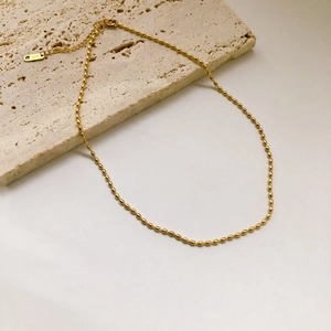 Elegante collana a catena di perline placcata oro 18K su superficie in pietra