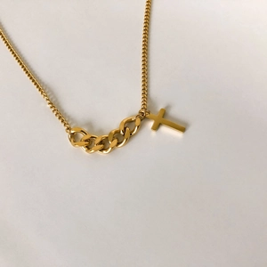 Détail d'un collier doré à maillons épissés avec un pendentif en forme de croix lisse