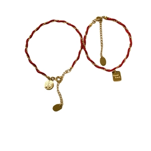 Red braided rope bracelet with golden Xi character and Good Luck charms on white background