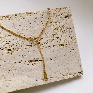 Dettaglio della collana a sfere in oro 18K con targhetta incisa K18 su base di pietra