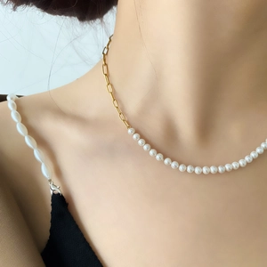 Close-up of pearl and gold paperclip chain necklace on neck showing texture