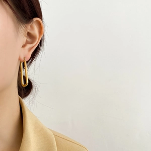 Primo piano di orecchini a cerchio dorati a forma di U su modella con blazer