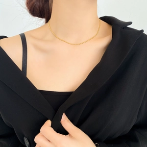 Dettaglio di una collana girocollo a sfere dorate minimalista indossata da una modella