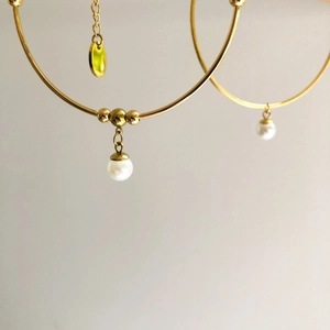 Detail view of gold hoop earrings featuring elegant white pearls and amber translucent drops
