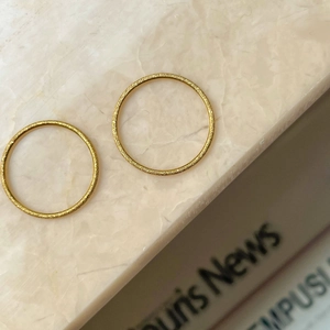 Close-up of two minimalist gold frosted matte rings on marble surface for daily styling