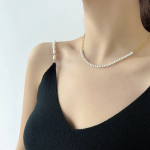 Minimalist pearl and gold chain necklace shown on a model with an elegant black top
