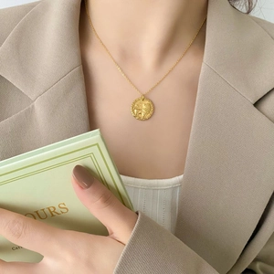 Dettaglio della collana con medaglia dorata, ciondolo a leone e catena sottile