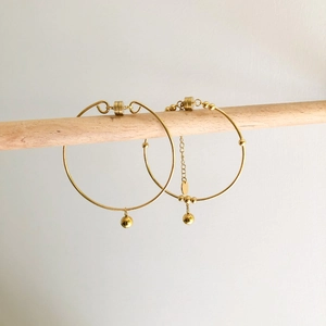 Minimalist gold bangle set with bead charms and magnetic clasp on wooden stand
