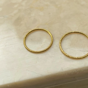 Detail of two gold matte frosted titanium steel rings on marble background