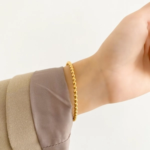 Close-up of a minimalist rose gold beaded bangle with high-gloss metallic finish