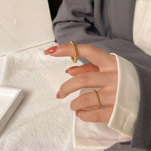 Minimalist gold beaded rings shown on fingers against a modern professional background