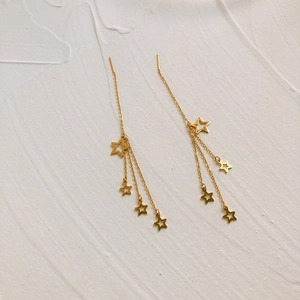 Detailed macro view of gold-plated star tassel earrings with long chains and star pendants